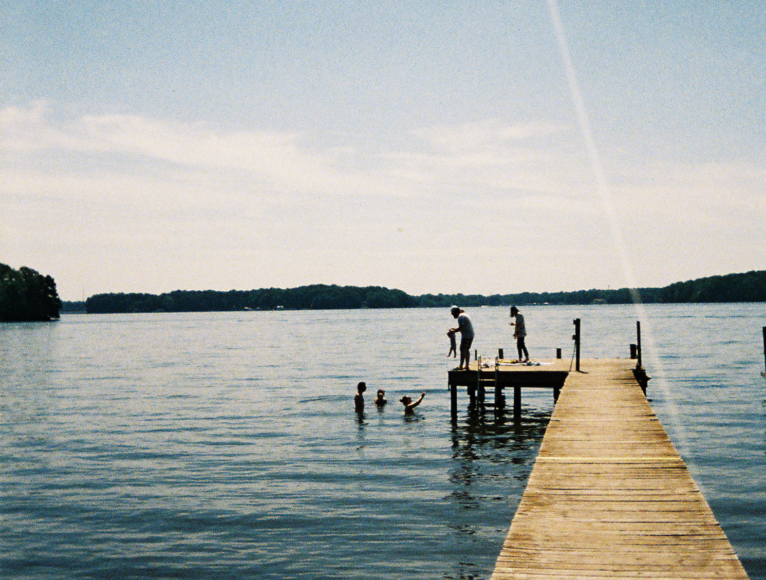 Friends swimming in a lake by a dock.